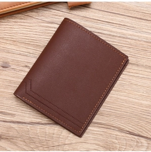 Detailed view of dark brown litchi grain leather bifold wallet on a wooden surface