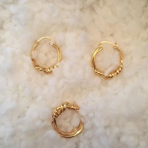 Detailed view of gold twisted knot earrings and matching ring set on white background