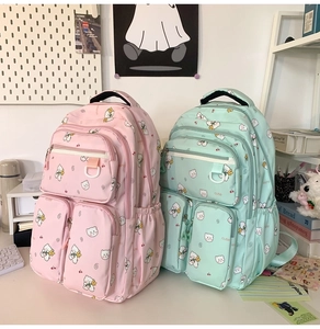 Detail of pink and green cute bear backpacks with multiple zipper pockets on a desk