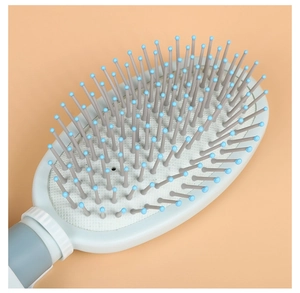 Detail view of oval hair brush with blue handle and grey bristles with massage tips