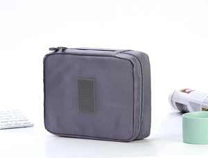 Detail of grey travel toiletry bag featuring double zippers and leather travel patch