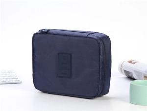 Close-up of a dark blue travel toiletry bag with leather TRAVEL logo and top handle