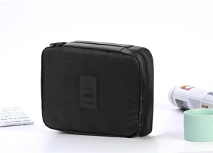 Close-up of black textured travel toiletry bag with dual zippers on a white desk