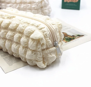 Detailed macro shot of creamy white bubble textured fabric on a high-capacity soft makeup bag