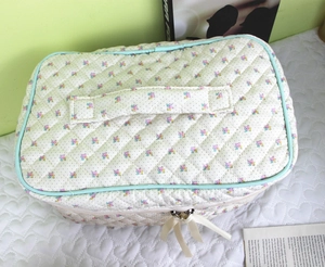 Detailed view of quilted floral makeup bag with blue pink flowers and green piping
