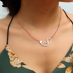 Close-up of rose gold stethoscope heart necklace worn by a model on floral top
