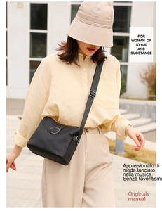 Outdoor lifestyle shot of a black nylon crossbody bag with silver buckle and adjustable strap