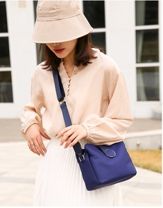 Blue nylon crossbody bag featuring a wide strap and metal buckle detail on the model