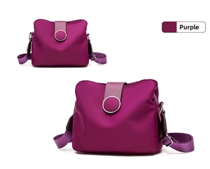 Detail of purple nylon crossbody bag showing glossy texture and silver metal ring buckle