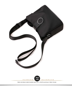 Detail of black nylon crossbody bag with silver metal ring and adjustable strap