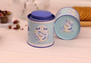 Close-up of a blue tin canister featuring a cute bunny illustration and floral decor