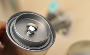 Detailed close-up of double-lid silver tin can showing the internal seal and metal handle