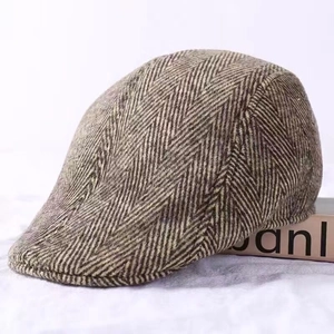Detail of brown herringbone wool newsboy cap showing thick textured fabric and brim