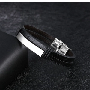 Detail of double-layer black leather bracelet with polished silver metal plaque and clasp