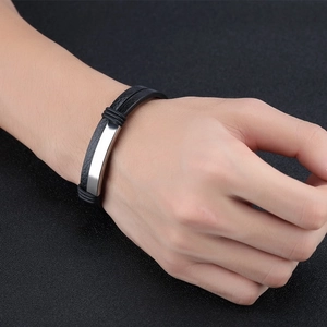 Close-up of black braided leather men's bracelet with a silver metal bar on wrist