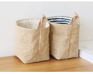 Close-up of small jute storage bags with striped lining and woven handles on wood table