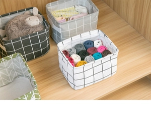 Foldable cotton linen storage bins with grid patterns shown organized in a wooden closet