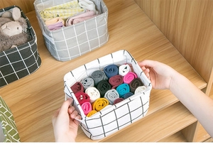 Detail showing hands holding a white checkered fabric basket filled with rolled socks