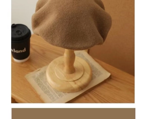 Detailed texture of brown wool beret hat placed on a wooden stand with vintage props