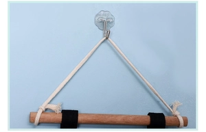 Detail of adhesive wall hook and wooden rod with cotton rope for bedside storage bag