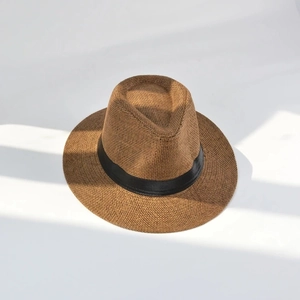 Close-up of brown straw Panama hat with black grosgrain ribbon on white background
