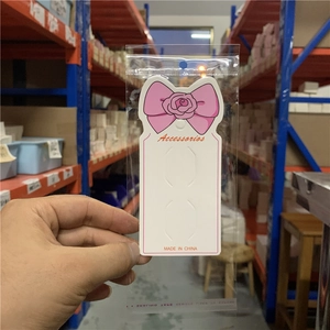 Detailed view of white paper earring display card with pink ribbon and rose illustration