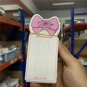 Detail of white jewelry display cards with pink bow design held in a warehouse setting
