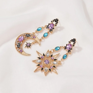 Macro view of gold sun and moon earrings with colorful crystals and black enamel finish