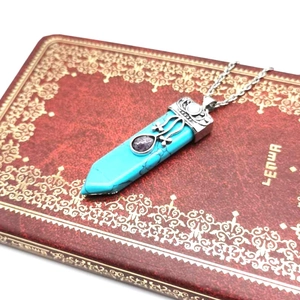 Detail of a vintage turquoise hexagonal sword necklace with purple gemstone accents