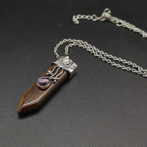 Close-up of tiger eye stone pendant with silver filigree and drop-shaped purple gem