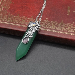Macro shot of green stone hexagonal pendant with vintage silver filigree on a red book