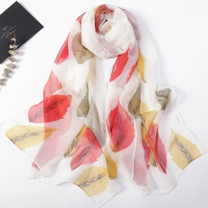 Macro detail of breathable chiffon scarf with vibrant colorful leaf patterns on white background