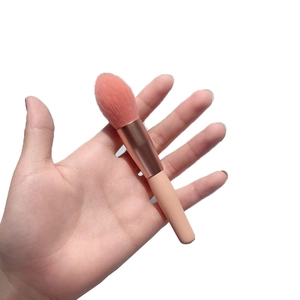 Pink soft bristle blush brush with rose gold ferrule held in hand for size display