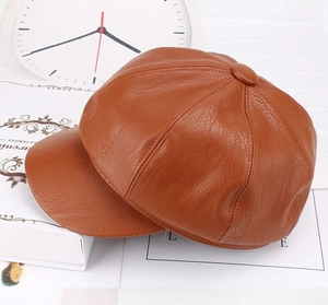 Detail view of brown octagonal newsboy cap with leather texture and top button detail