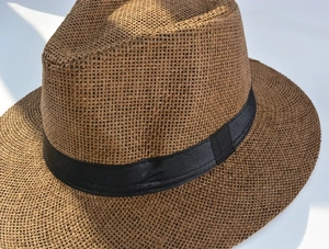 Macro shot of the brown straw weave texture and black decorative ribbon on the sun hat