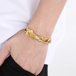 Close-up of a gold punk dragon scale Cuban chain bracelet on a male model's wrist