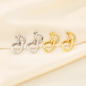 Detail of twisted Cuban chain stud earrings in gold and silver finish on silk fabric