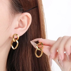 Close-up of interlocking gold geometric chain link earrings on model for a trendy look