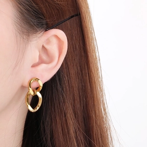 Close-up of elegant gold twisted Cuban chain earrings worn on model's ear