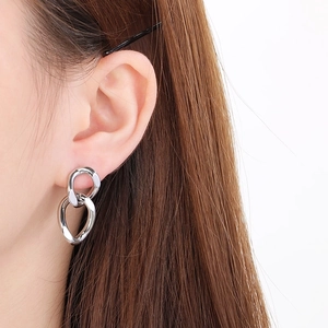 Close-up of polished silver stainless steel twisted link earrings on model's ear