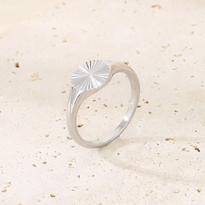Minimalist silver sunflower stainless steel ring with radial sunburst texture on beige base