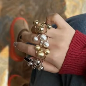 Anillos ajustables en oro y plata con bolas de metal y perlas en la mano