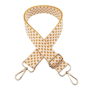 Close-up of yellow and white woven wide adjustable bag strap with gold metal buckles