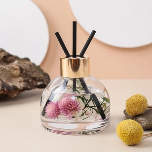 Close-up of glass car diffuser bottle with pink dried flowers and black reed sticks