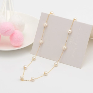 Detailed view of S925 silver necklace featuring round white pearls on a gold-plated chain