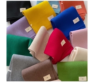 Close-up of stacked colorful knitted scarves showing textured fabric and brand labels