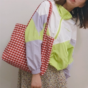 Close-up of red and white gingham tote bag worn as a shoulder bag on a model