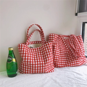 Detail of red and white gingham canvas tote bags set with a green Perrier bottle