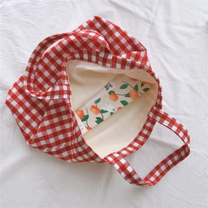 Detail view of red and white checkered tote bag with beige cotton lining and prop card