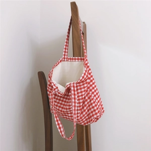 Detail of red and white gingham canvas tote bag hanging on a vintage brown wooden chair